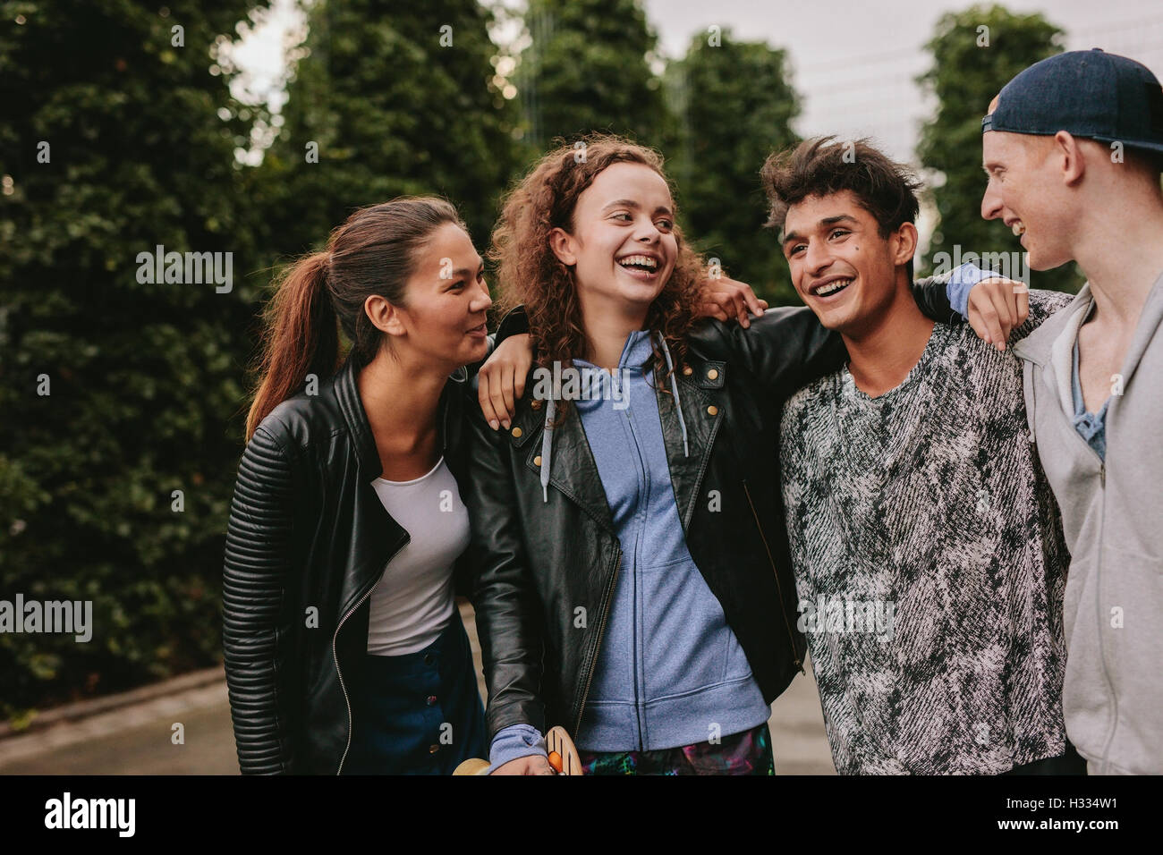 Portrait of four young friends together smiling. Mixed race group of people having fun outdoors. Stock Photo