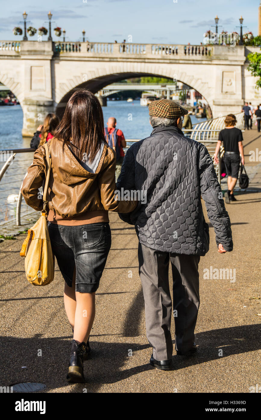 A young woman walks with her father near the River Thames in Kingston-Upon-Thames in Surrey, England, UK Stock Photo