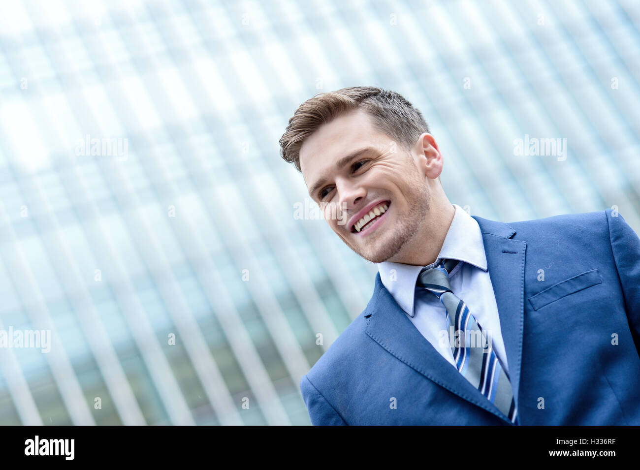 Young smiling man on modern building background Stock Photo - Alamy