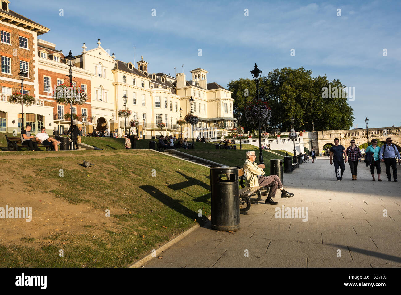 An elderly man sitting in front of exclusive riverside residential property overlooking the River Thames at Richmond Upon Thames, London, England Stock Photo