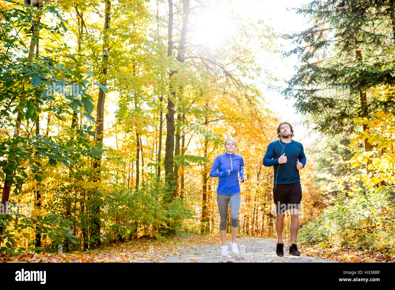Beautiful couple running outside in sunny autumn forest Stock Photo - Alamy