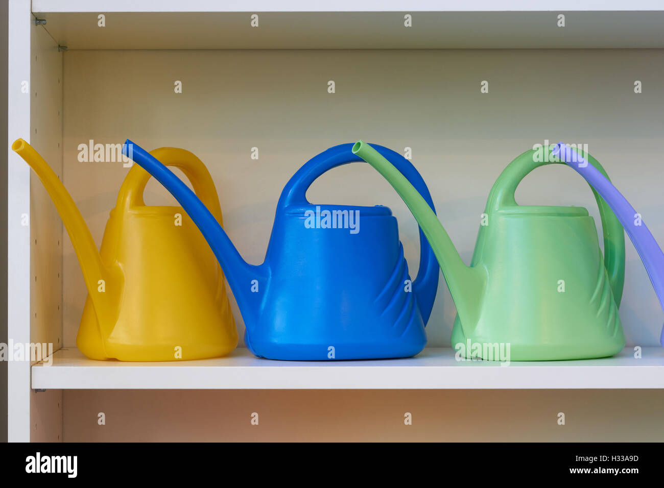 Three watering cans for watering flowers on the shelf Stock Photo
