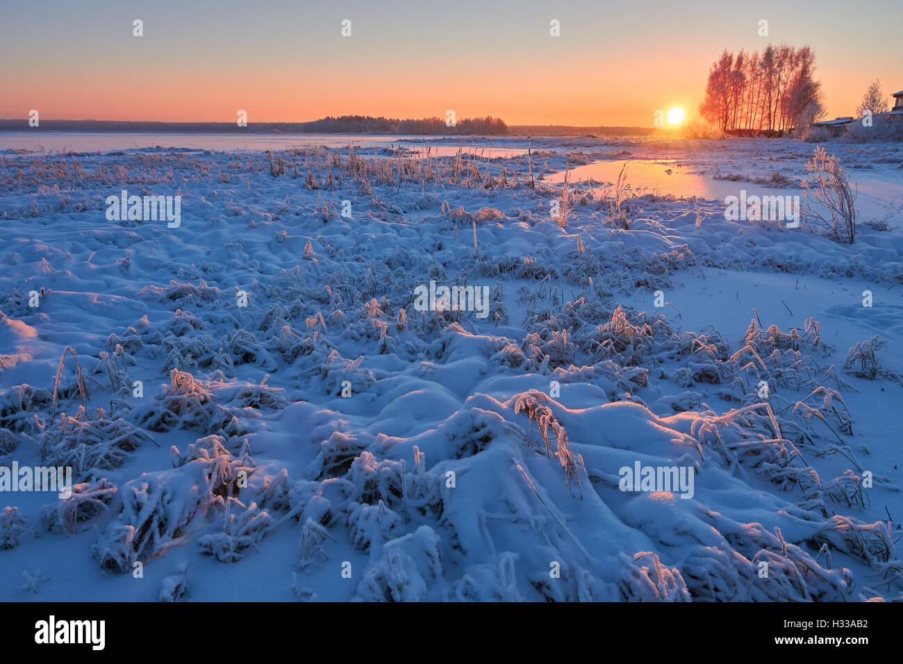 Sunrise in cold winter morning and sparkling snow in the countryside near the lake Stock Photo
