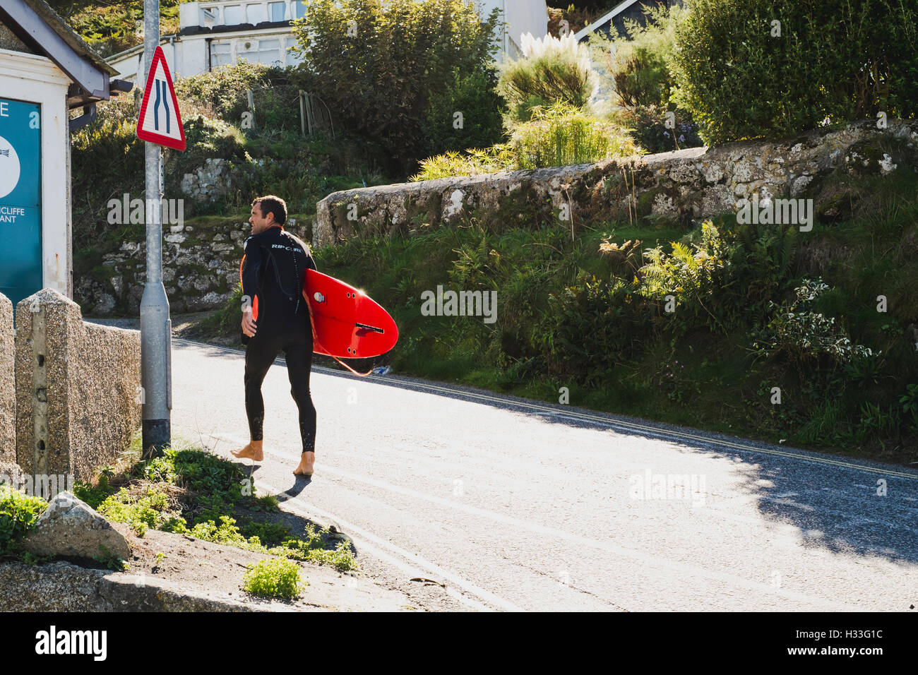 A surfer walking his board, Sennen Cove, Cornwall Stock Photo