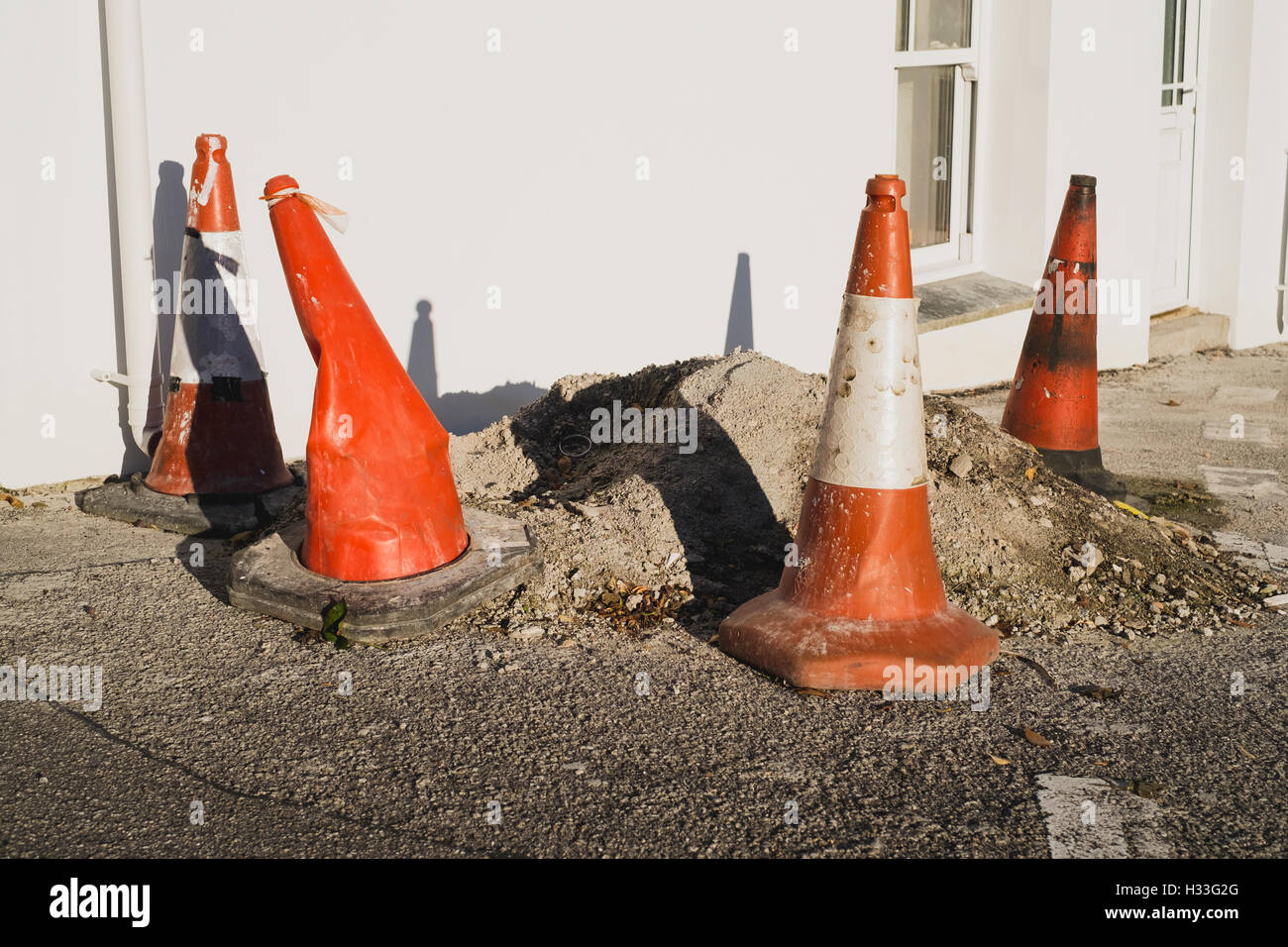 Red and white traffic cones surrounding a mound of waste on a roadside Stock Photo