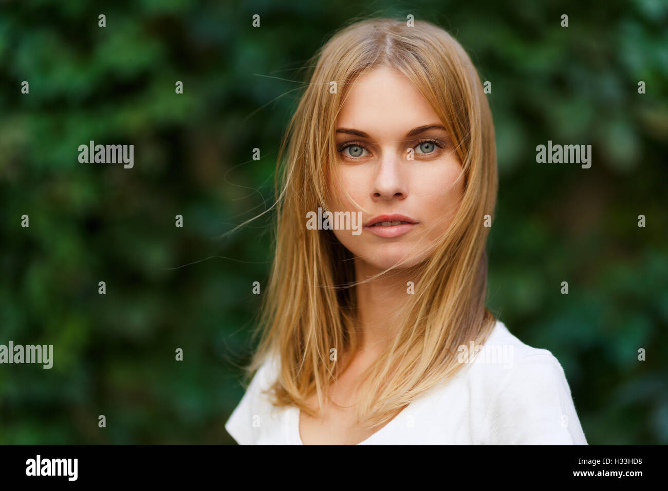 Portrait of beautiful woman on background green trees Stock Photo - Alamy
