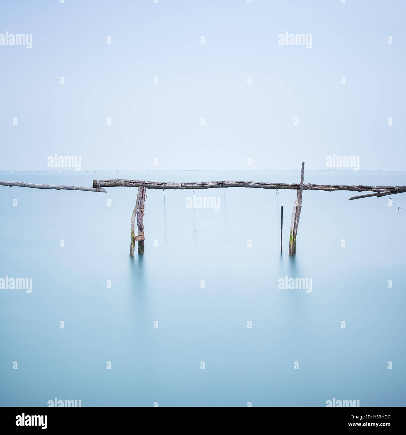 Fishing poles for clams and mussels and soft water on a quiet water landscape. Long exposure photography Stock Photo