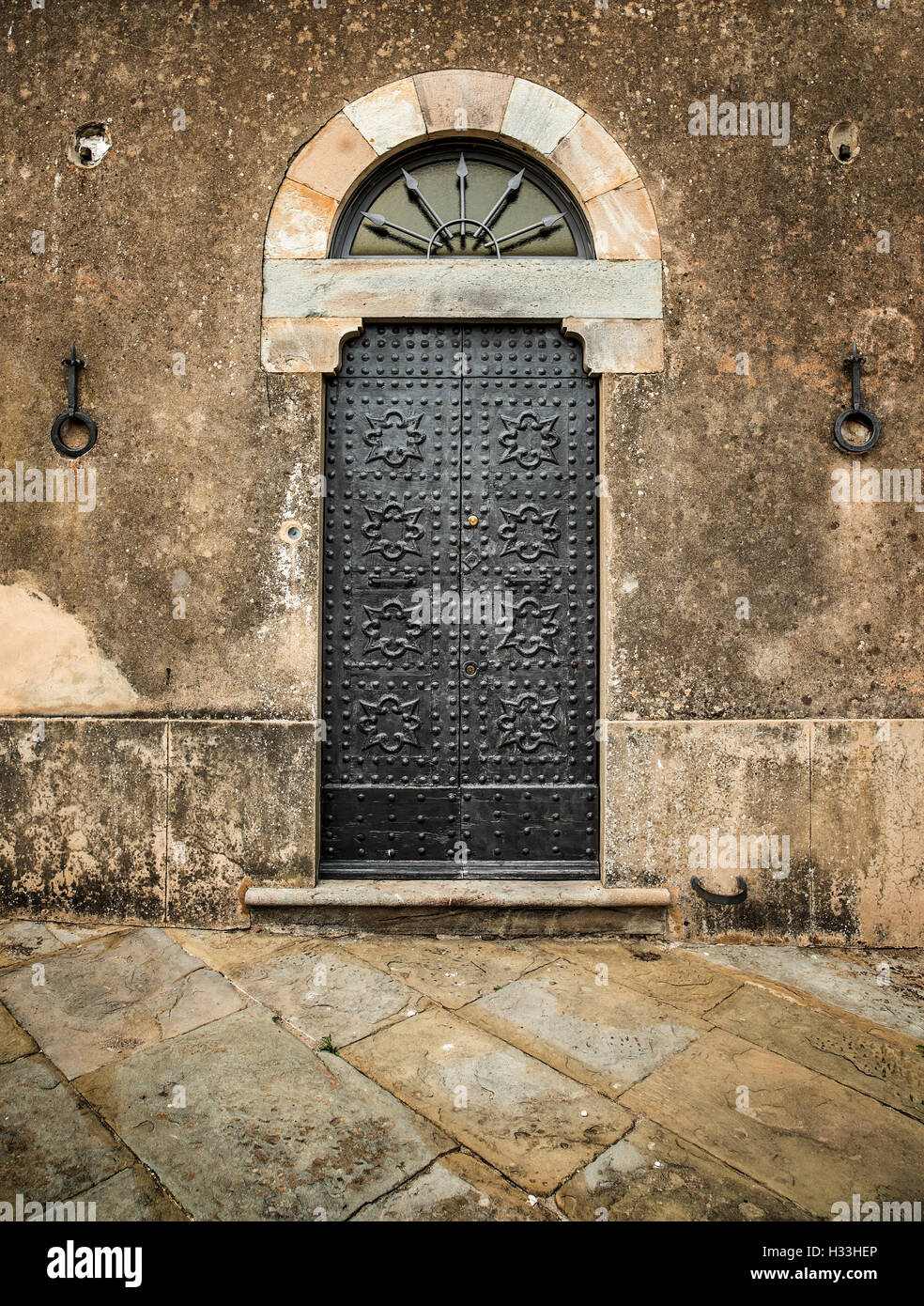 Traditional old vintage iron door and grunge wall in Tuscany, Italy, Europe. Stock Photo