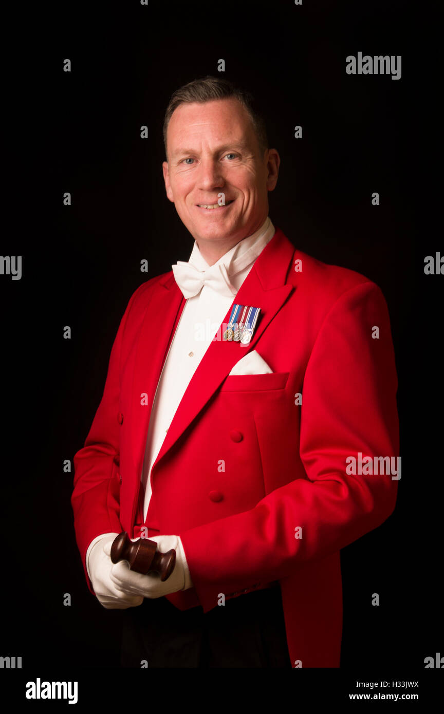 Toastmaster against a black background in traditional red jacket with