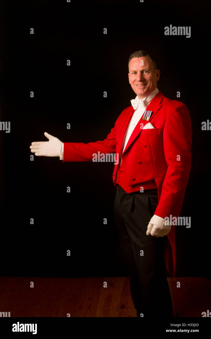 Toastmaster against a black background in traditional red jacket with