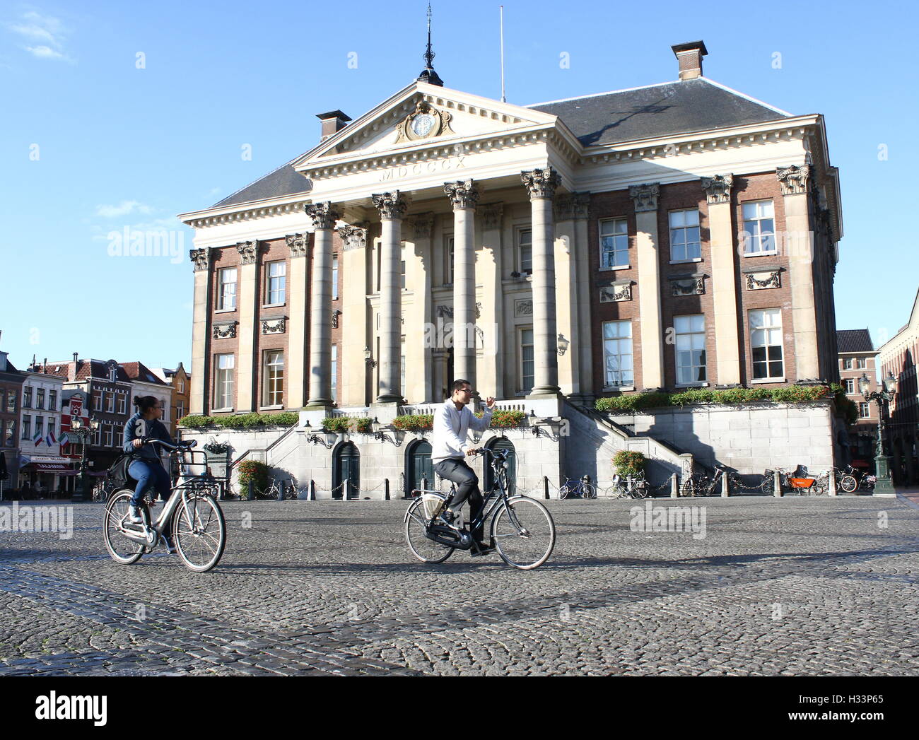 Asian students cycle in front of City Hall (stadhuis) on Grote Markt (Main Square), Groningen, Netherlands Stock Photo