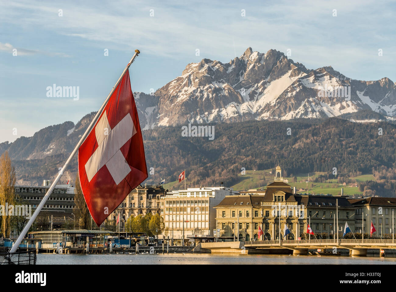 Swiss National Flag in Lucerne in Central Switzerland with the mountain range of Mt Pilatus in the background Stock Photo