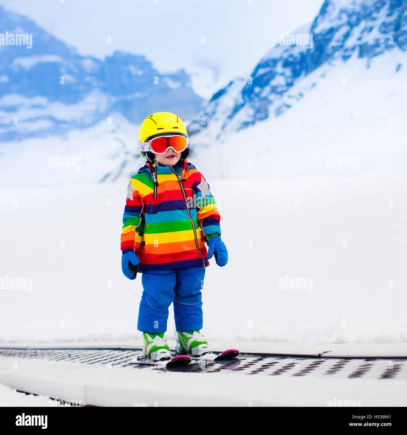 Child skiing in mountains. Active toddler kid with safety helmet