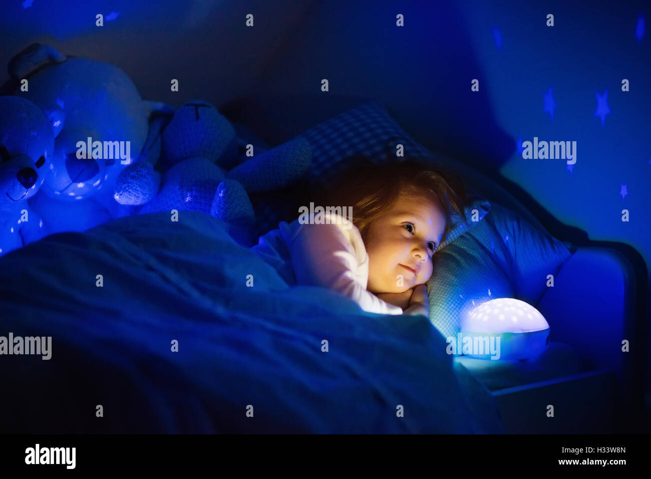 Little Girl Reading A Book In Bed Dark Bedroom With Night