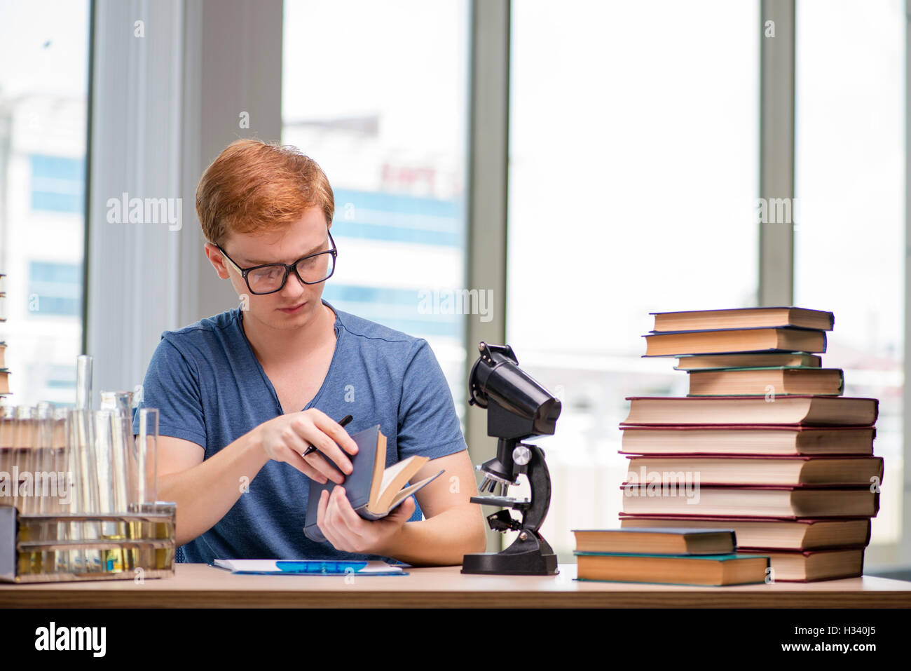 Young student tired and exhausted preparing for chemistry exam Stock