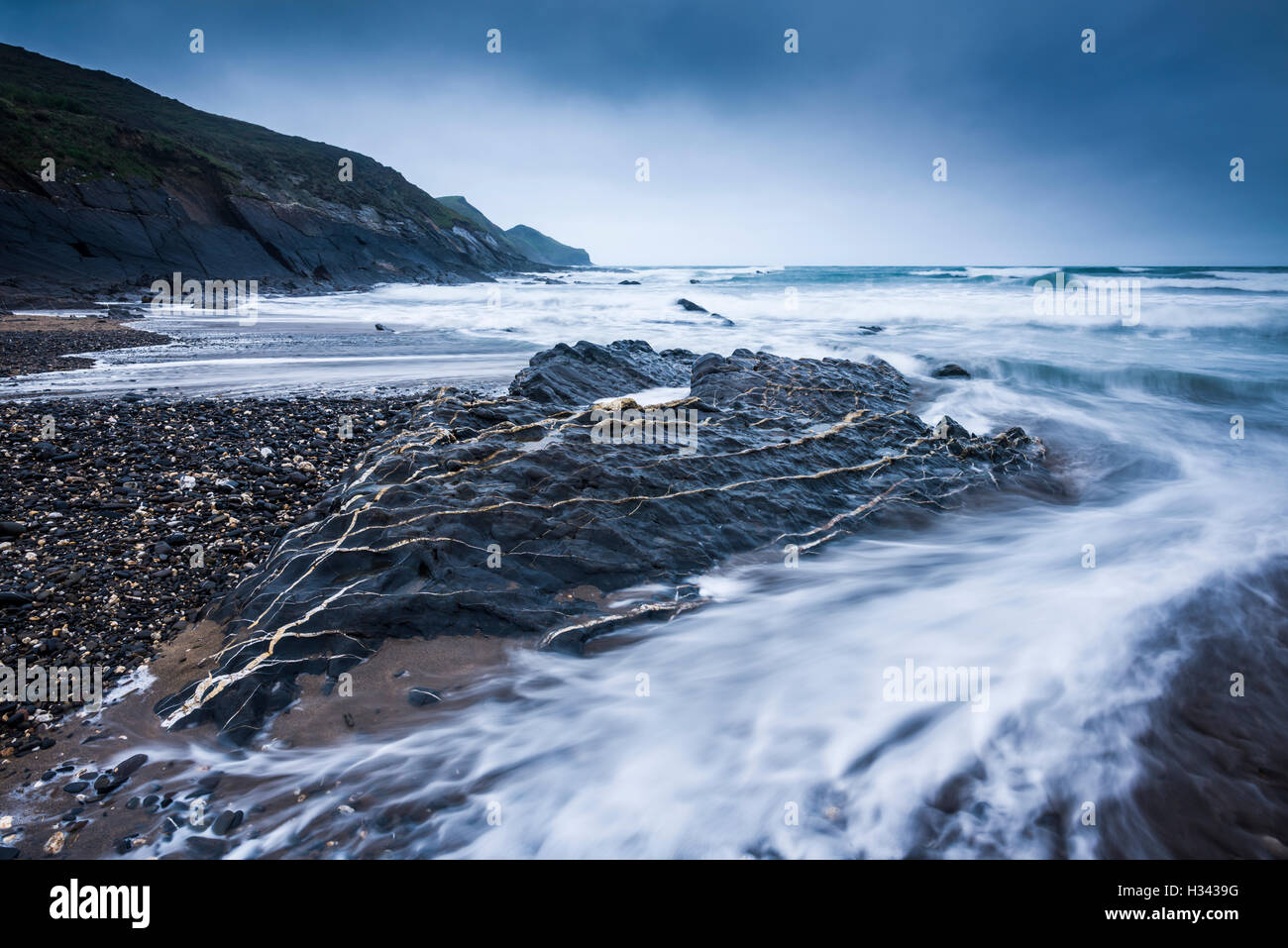 The incoming tide and rocks on the beach at Crackington Haven with the headland of Cambeak beyond on the North Cornwall coastline. England. Stock Photo
