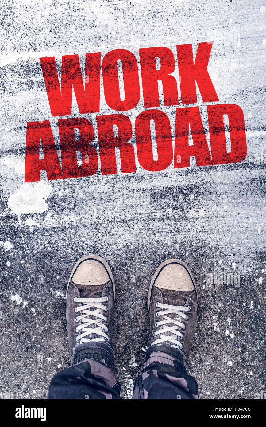 Work abroad title on the pavement above which is young male student standing and making decision to travel to foreign country an Stock Photo