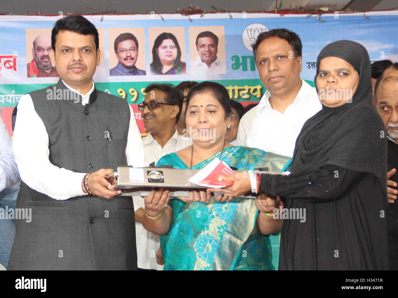 Maharashtra Chief Minister Devendra Fadnavis (L) distributes gas stoves to underpriviledged women after cutting a cake Mumbai Stock Photo