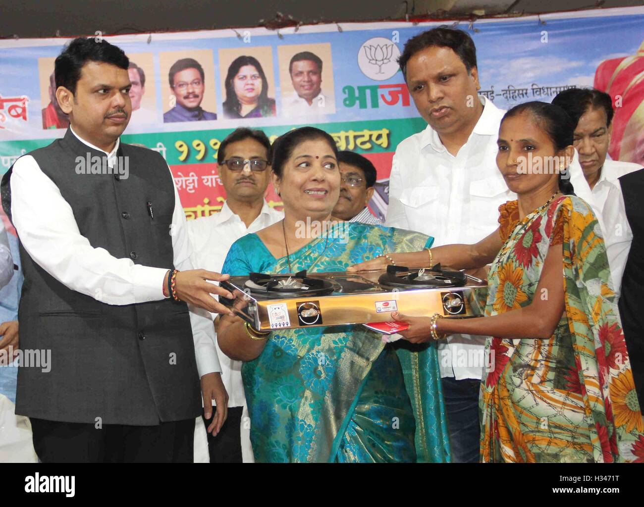Maharashtra Chief Minister Devendra Fadnavis (L) distributes gas stoves to underpriviledged women after cutting cake Mumbai Stock Photo