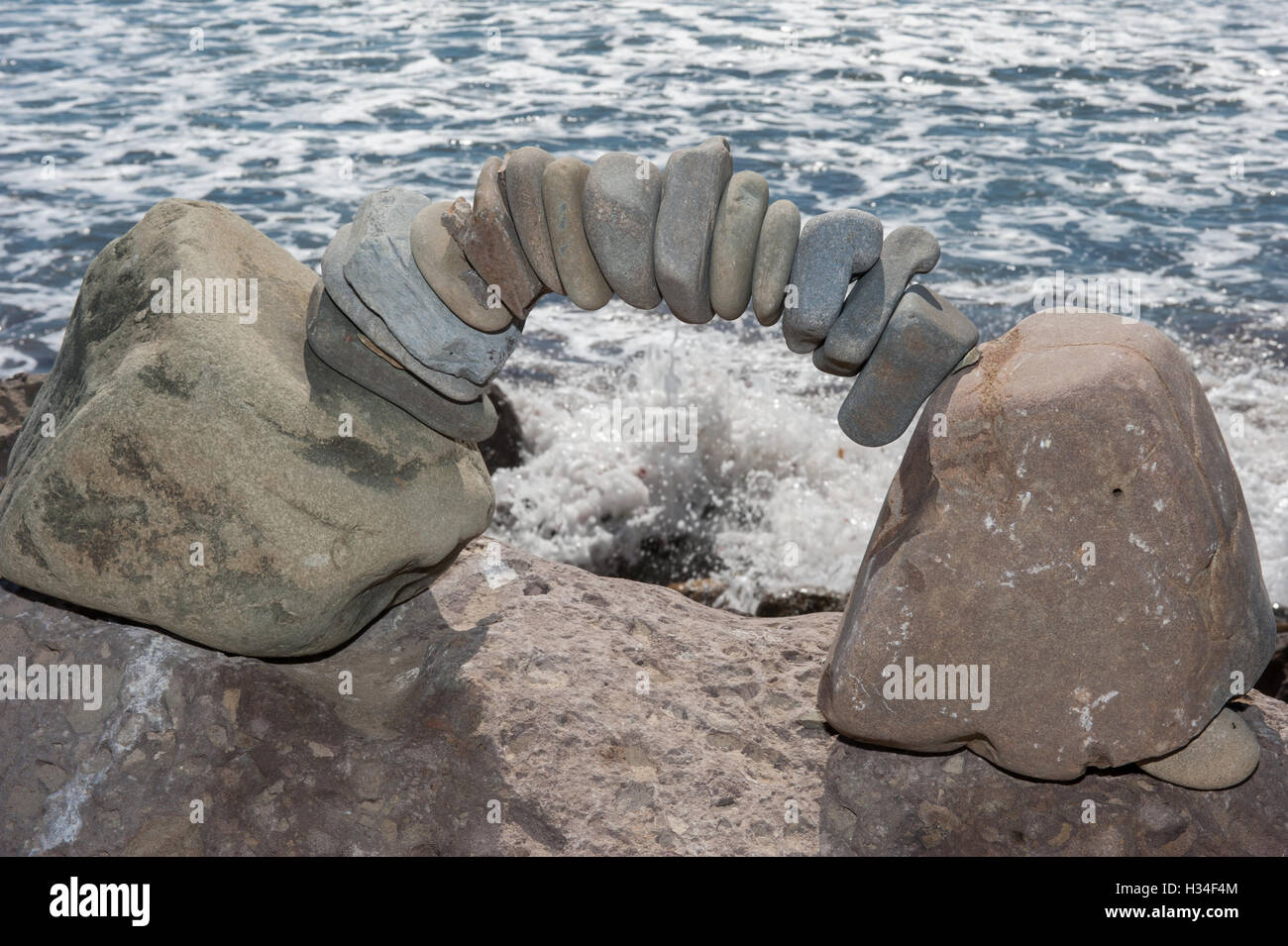 Pacific Ocean waves framed by delicate arch of rocks. Stock Photo