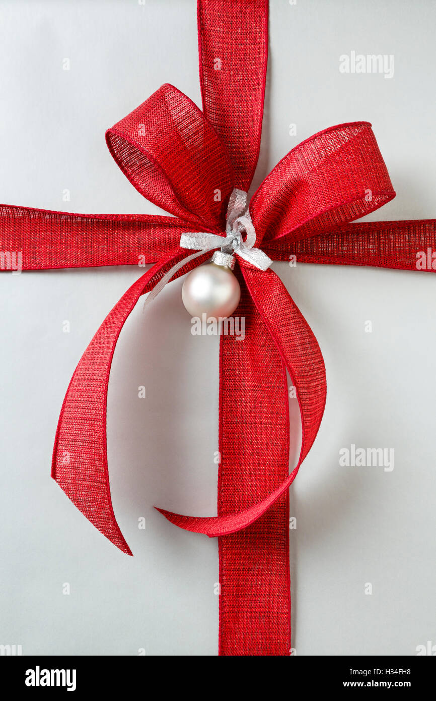 Close up of red bow on classic Christmas gift Christmas present background with silver wrapping paper Stock Photo