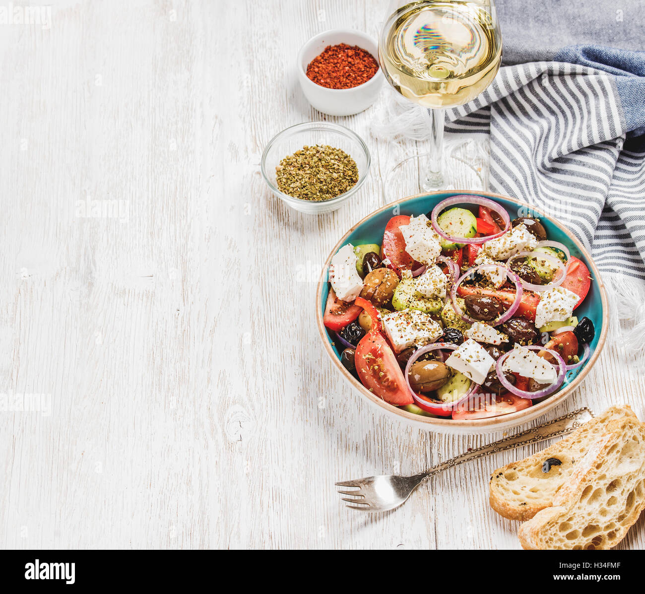 Greek salad with bread, herbs and glass of white wine Stock Photo