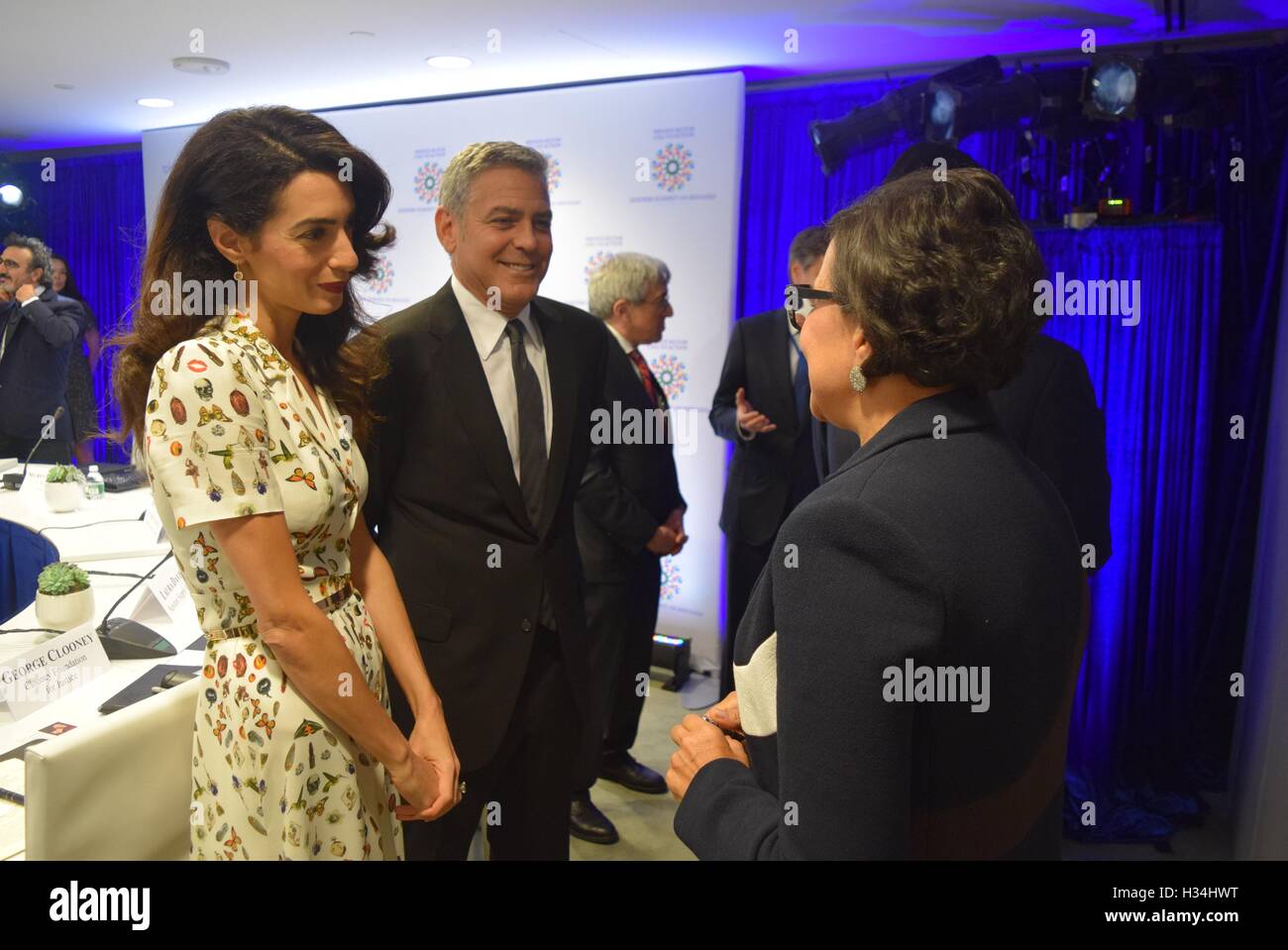Actor George Clooney and wife Amal Alamuddin (L) chat with U.S. Commerce Secretary Penny Pritzker (R) before the start of a Roundtable Summit for Refugees at the United Nations September 20, 2016 in New York City, New York. Stock Photo