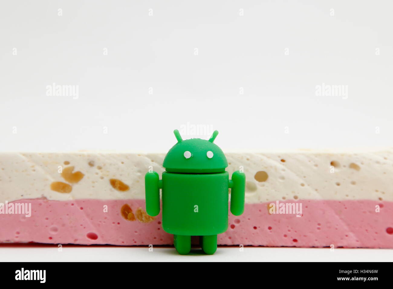 The Android robot loiters in front of a bar of nougat. Stock Photo