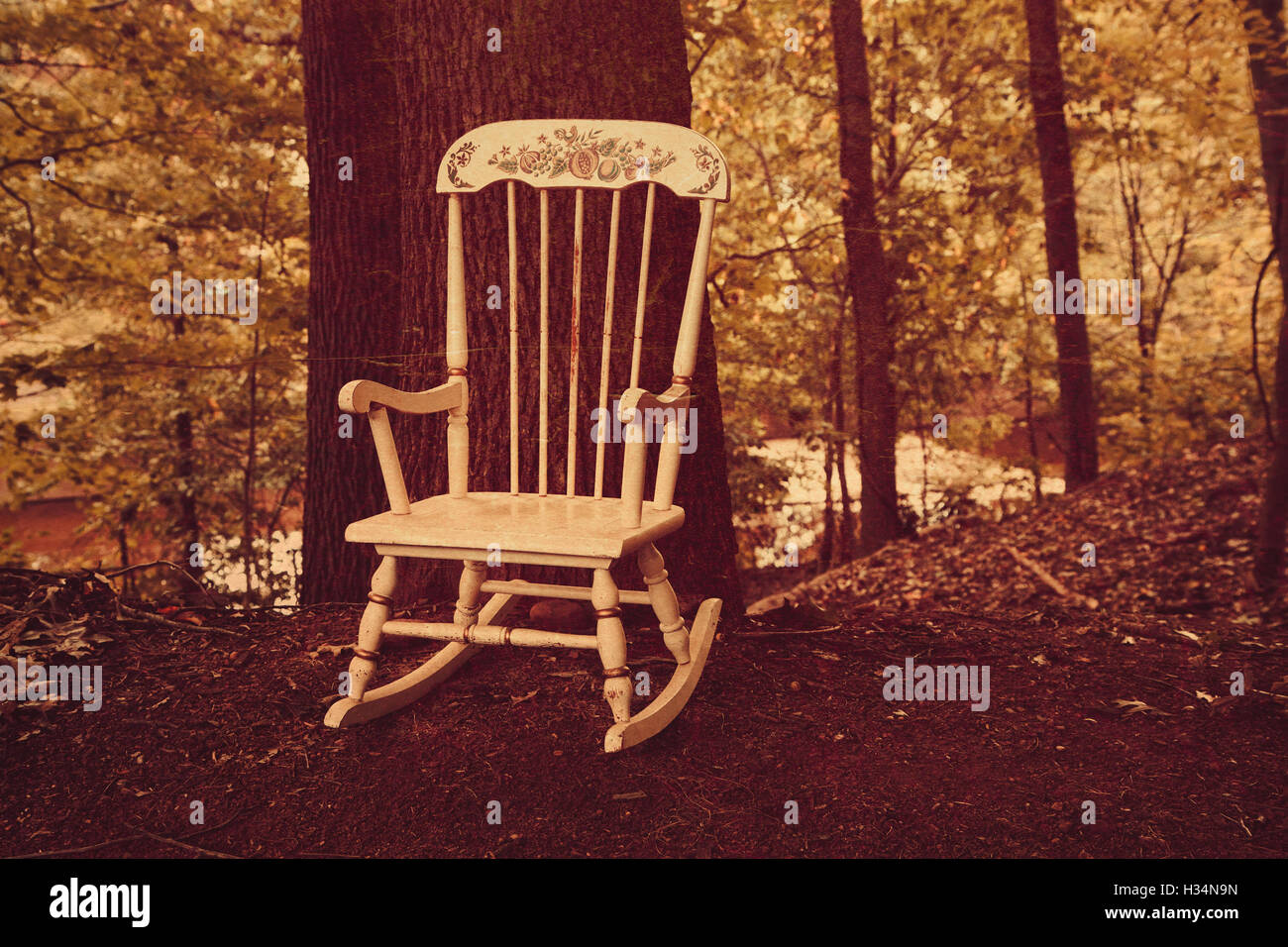 A vintage child's rocking chair sits in the middle of the woods. Stock Photo