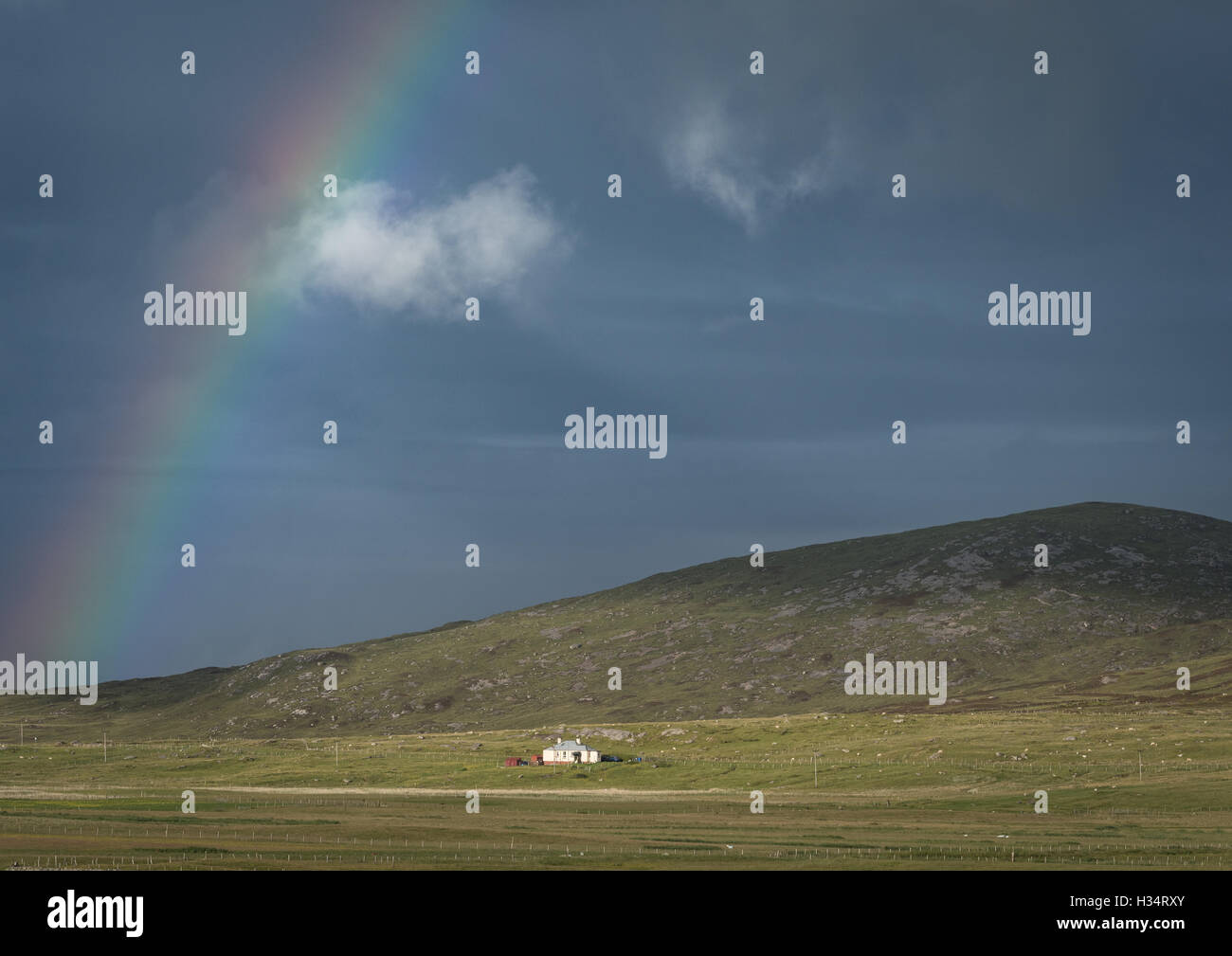 Rainbow and cloud over hill and house on the Island of Berneray, Outer Hebrides, Western Isles, Scotland Stock Photo