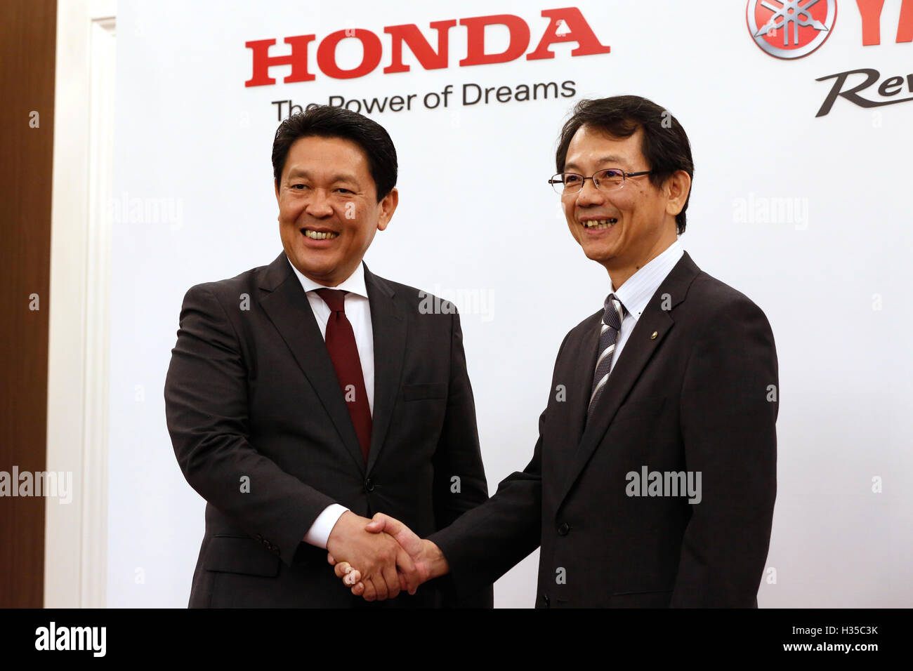 Honda Motor Operating Officer and Director Shinji Aoyama, left, shakes hands with Yamaha Motor Managing Executive Officer and Director Katsuaki Watanabe during a joint press conference in Tokyo, Japan on October 5, 2016. Japanese auto majors Honda and Yamaha announced they have started talks toward a business tie-up in the development and production of small scooters. © Yosuke Tanaka/AFLO/Alamy Live News Stock Photo