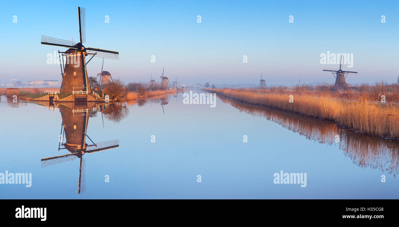 Traditional Dutch windmills reflected in perfectly still water on a cold morning in winter, at the Kinderdijk in The Netherlands Stock Photo