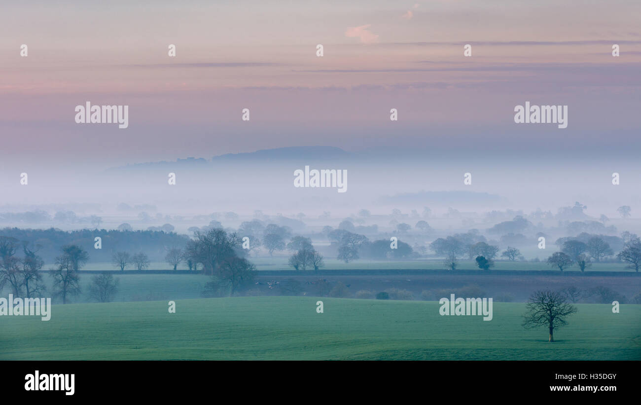 A spring dawn morning with mist lying in the Cheshire plain extending to the Peckforton Hills and Beeston Castle, Cheshire, UK Stock Photo