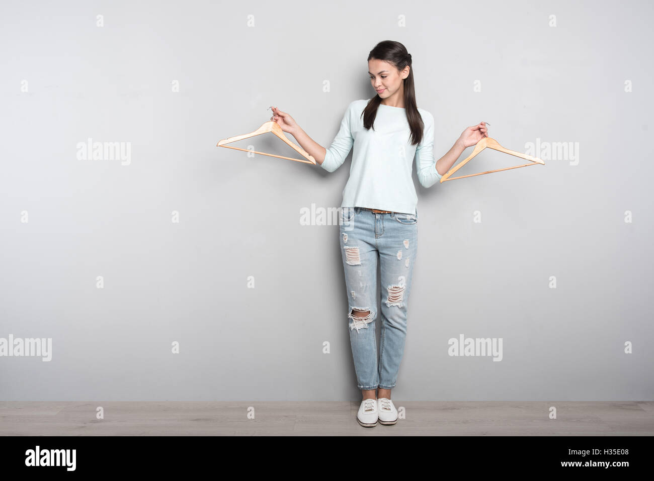 Peasant delighted woman holding clothes hangers. Stock Photo