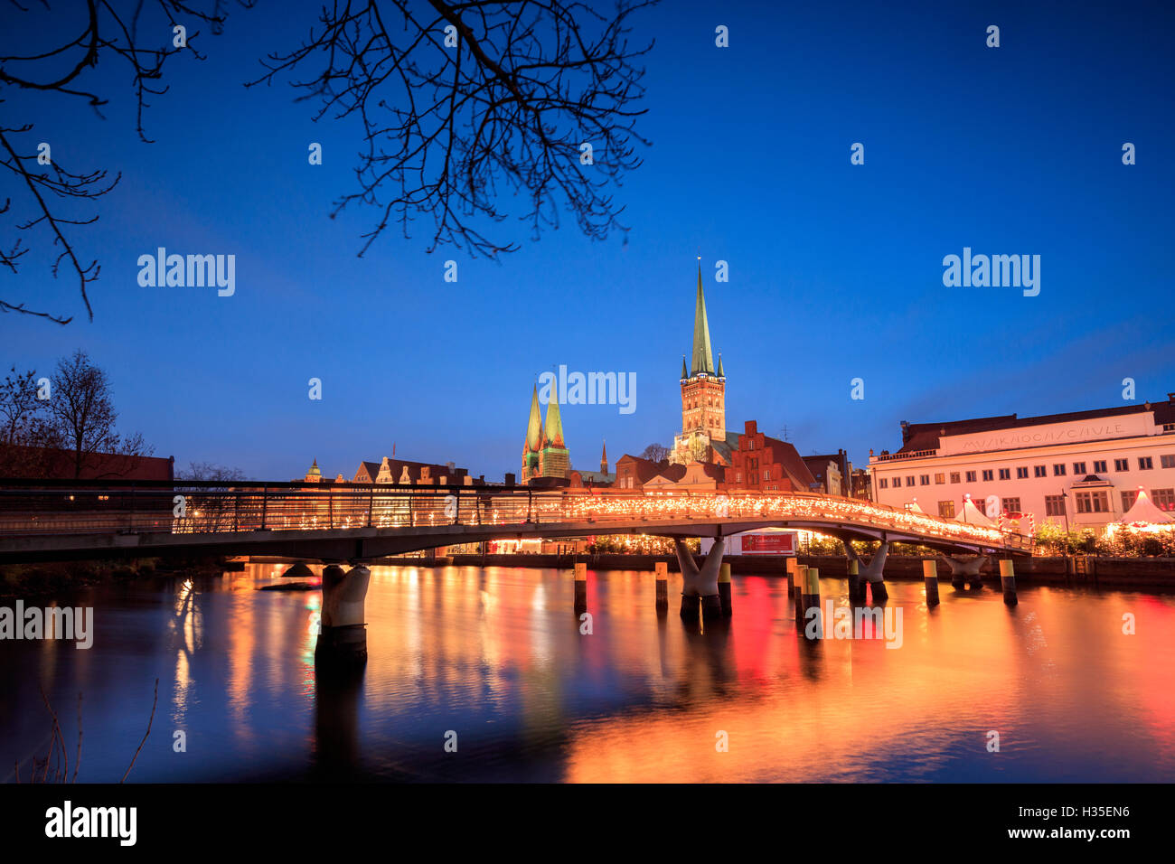 The lights of dusk on typical bridge and the cathedral reflected in River Trave, Lubeck, Schleswig Holstein, Germany Stock Photo