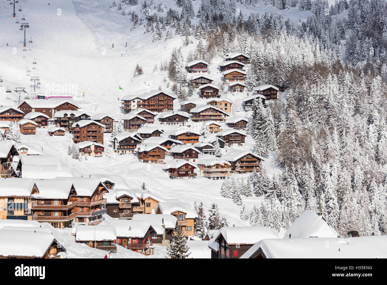 Snowy woods frame the typical alpine village and ski resort, Bettmeralp, district of Raron, canton of Valais, Switzerland Stock Photo