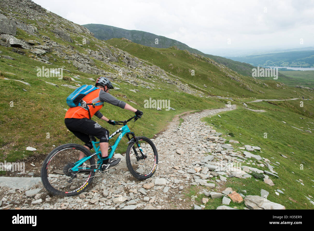 A mountain biker descends the trail from The Old Man of Coniston in the Lake District National Park, Cumbria, England, UK Stock Photo