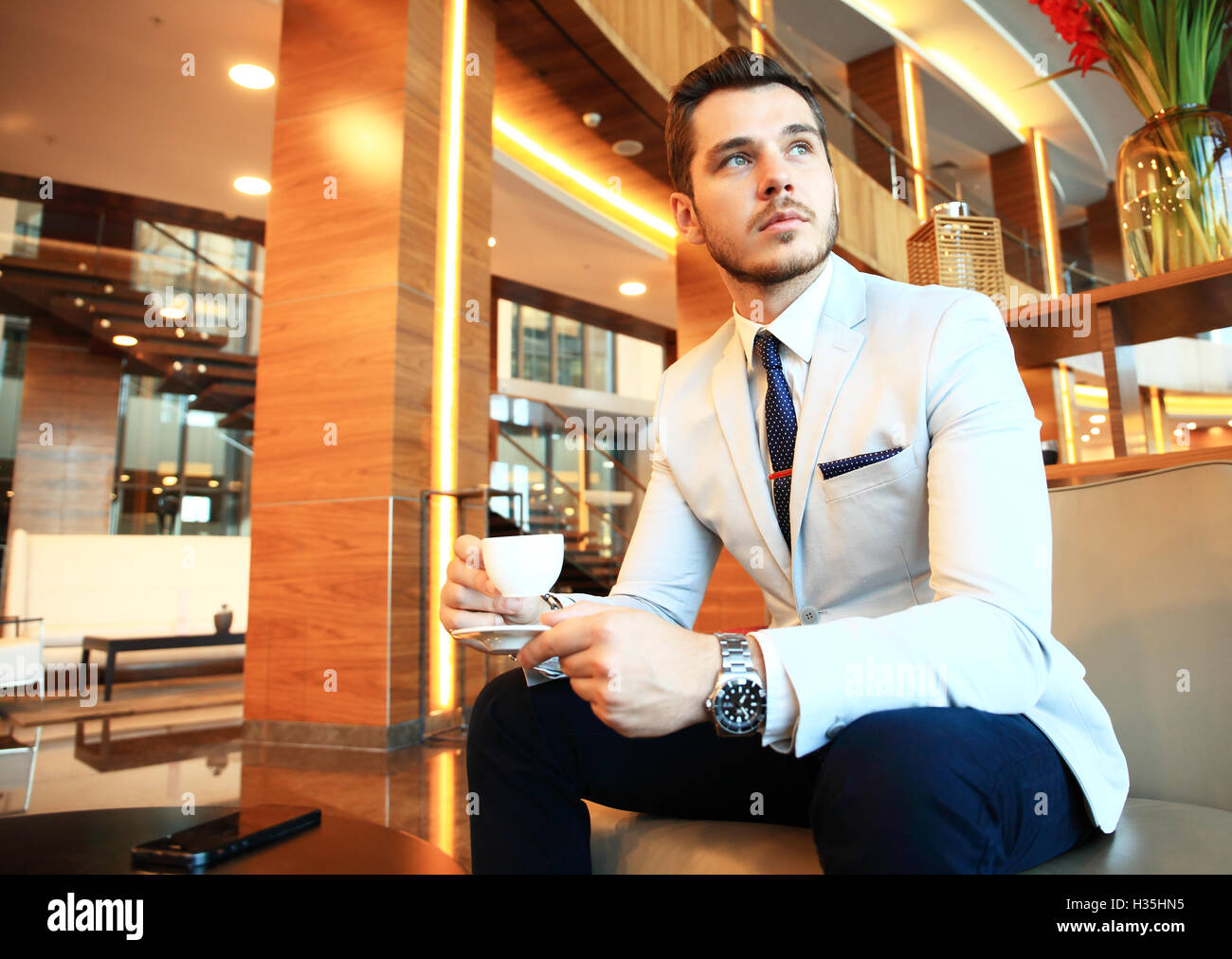 Portrait of handsome successful man drink coffee sitting in coffee shop, business man having breakfast at hotel lobby. Stock Photo