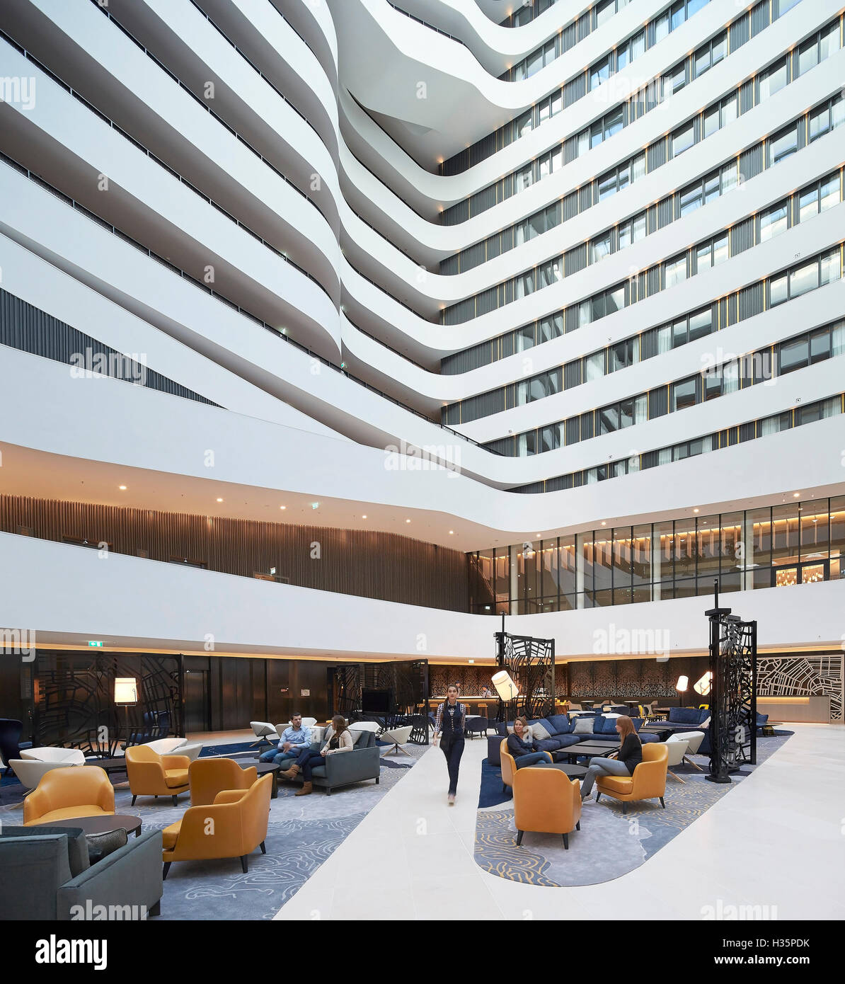 Lounge and reception in full-height atrium. Hilton Amsterdam Airport Schiphol, Amsterdam, Netherlands. Architect: Mecanoo Architects, 2015. Stock Photo