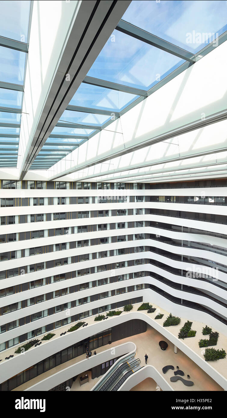 Atrium with glass ceiling viewed from upper level. Hilton Amsterdam Airport Schiphol, Amsterdam, Netherlands. Architect: Mecanoo Architects, 2015. Stock Photo