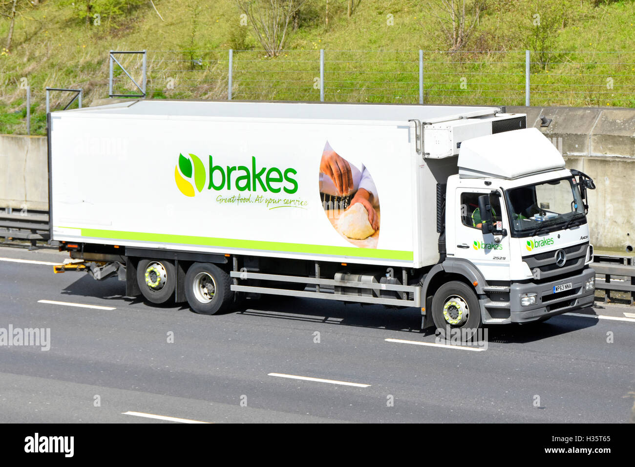 Front & side view of Brakes wholesale logistical services company food and drink distribution lorry on English UK motorway with product advertisement Stock Photo