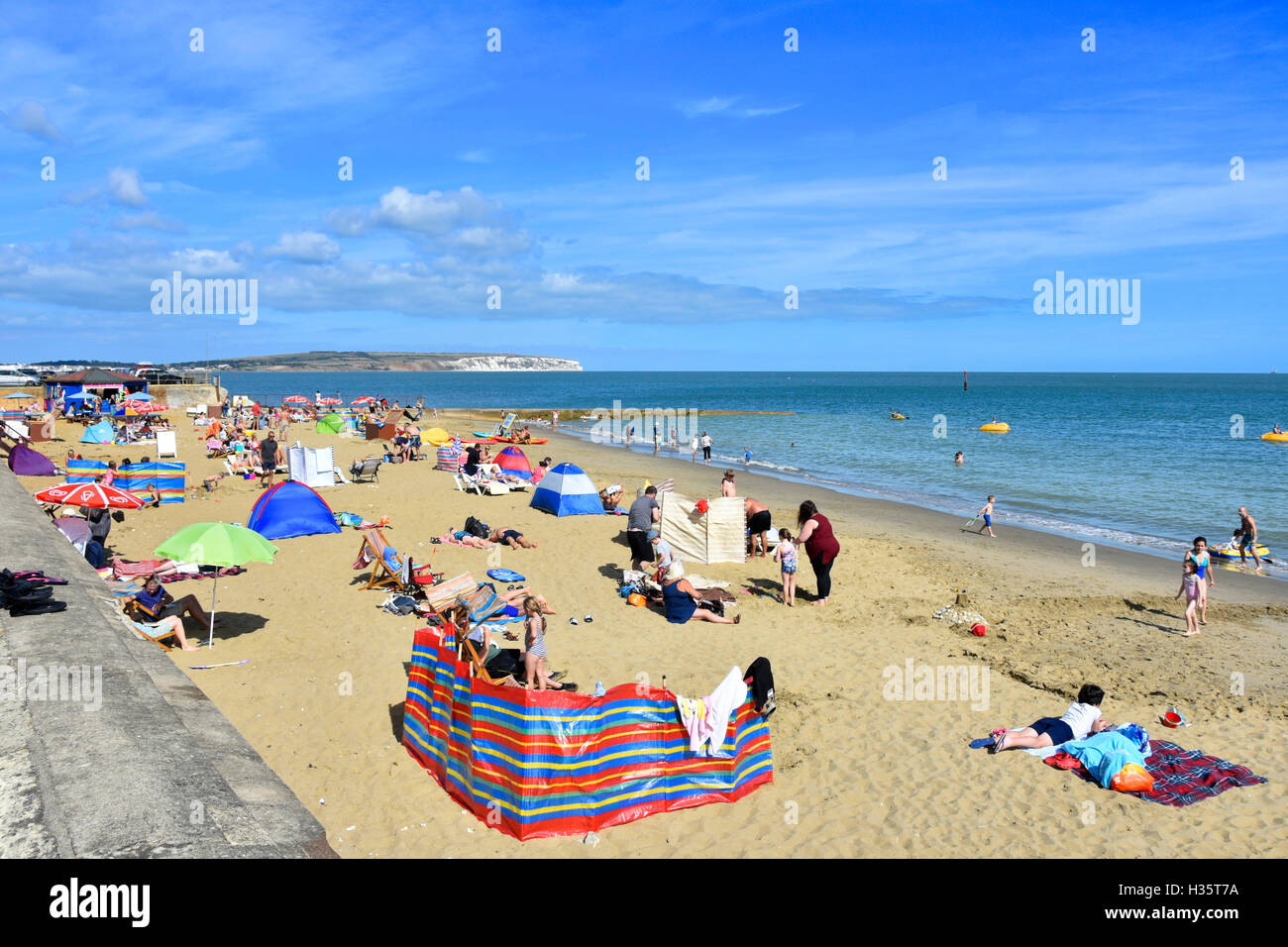 Busy sandy UK English summer holiday family beach at Shanklin on the Isle of White hot summers day with white Culver Cliff distant along coastline Stock Photo