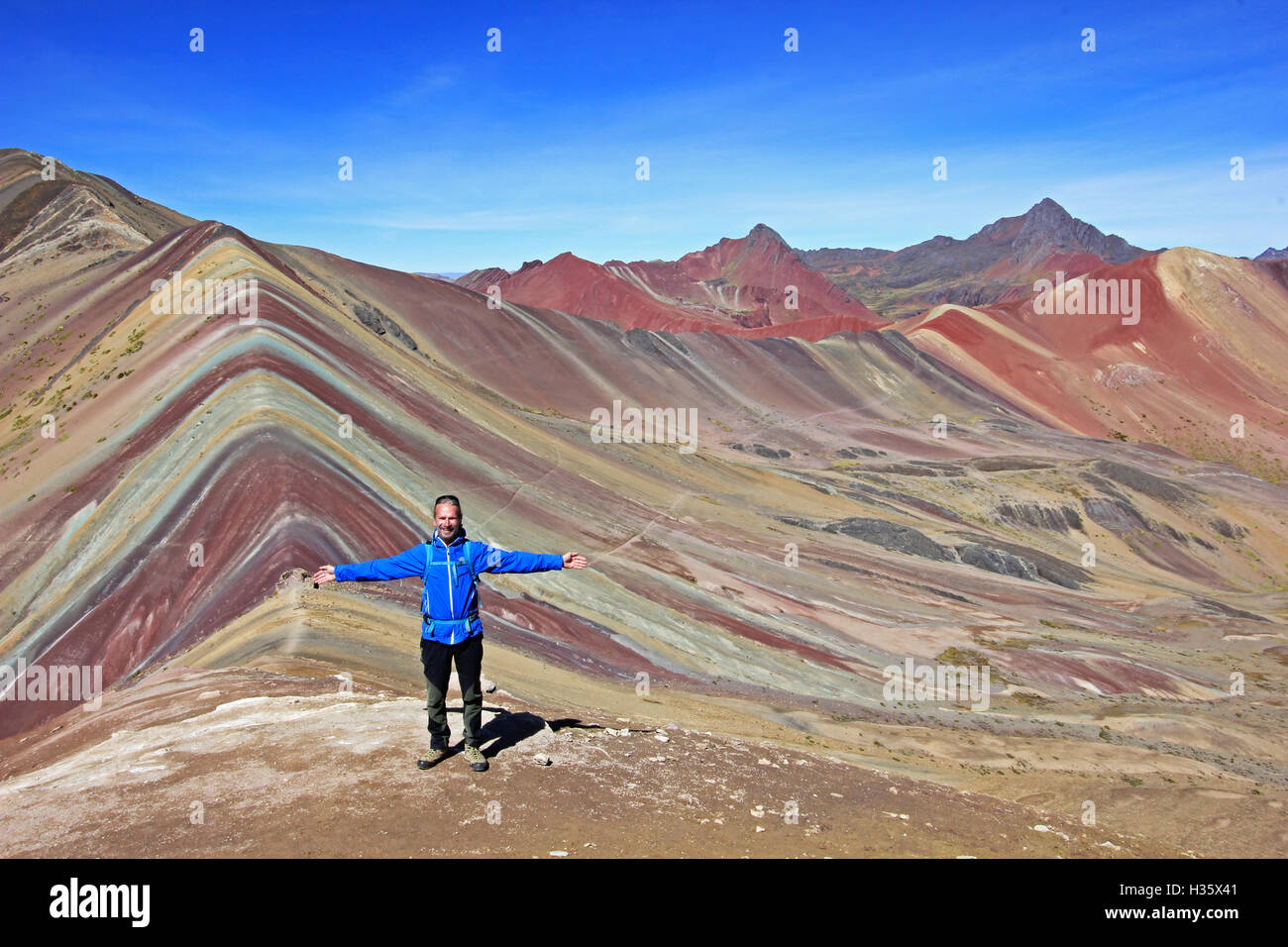 The photographer posing in front of the beautiful colored Rainbow Mountain panorama near Cusco Peru. Nice view into the valley Stock Photo