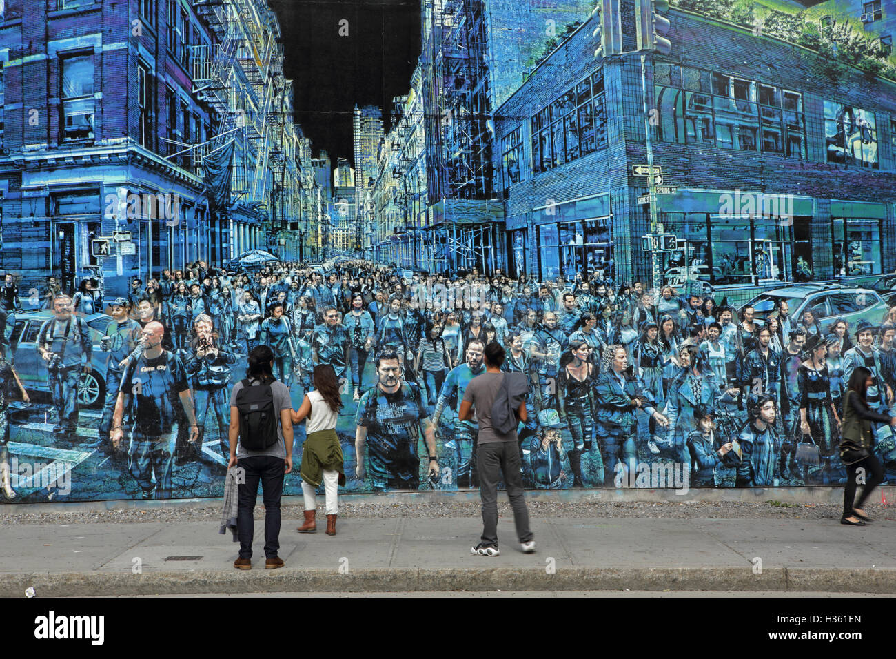 NYC pedestrians walk past a large mural painted by Logan Hicks on the Bowery Mural Wall, Houston Street Stock Photo