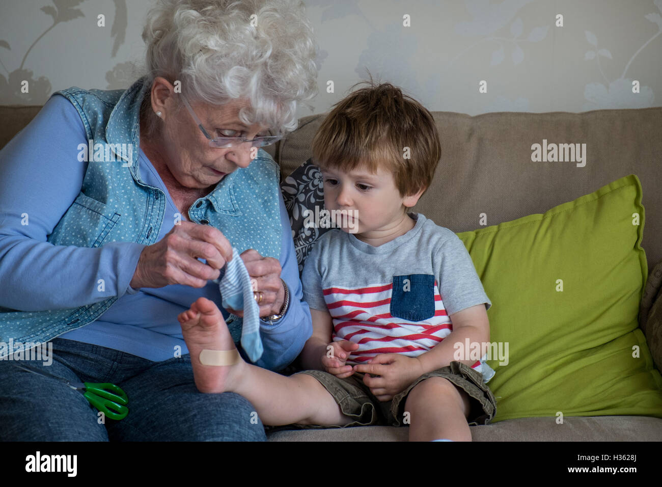 Grandmother puts plaster on grandson's foot Stock Photo