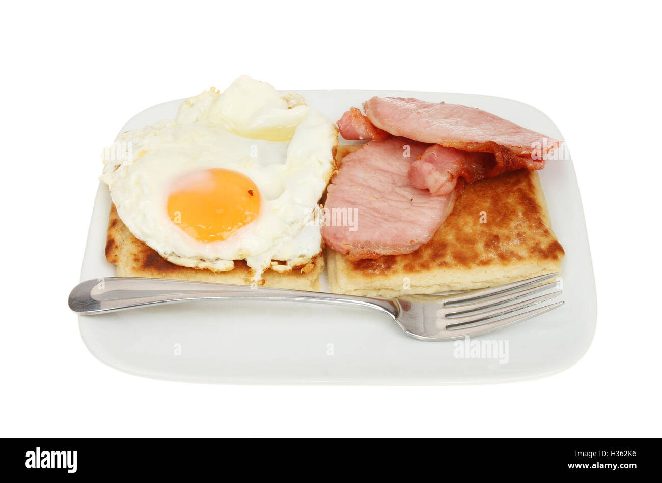 Fried egg, bacon and Irish potato bread with a fork on a plate isolated against white Stock Photo