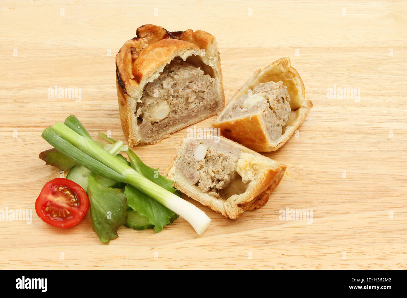 Pork pie and salad on a wooden chopping board Stock Photo