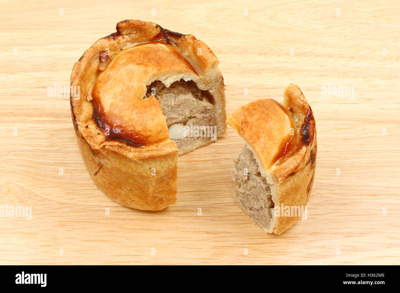 Handmade hot water pastry pork pie with a slive cut out on a wooden
