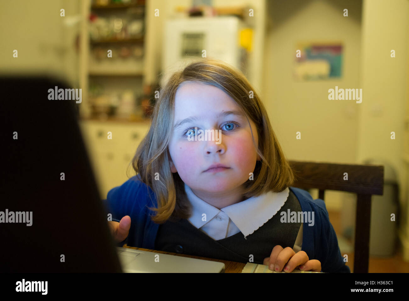Little girl at computer looks thoughtfully out the picture Stock Photo
