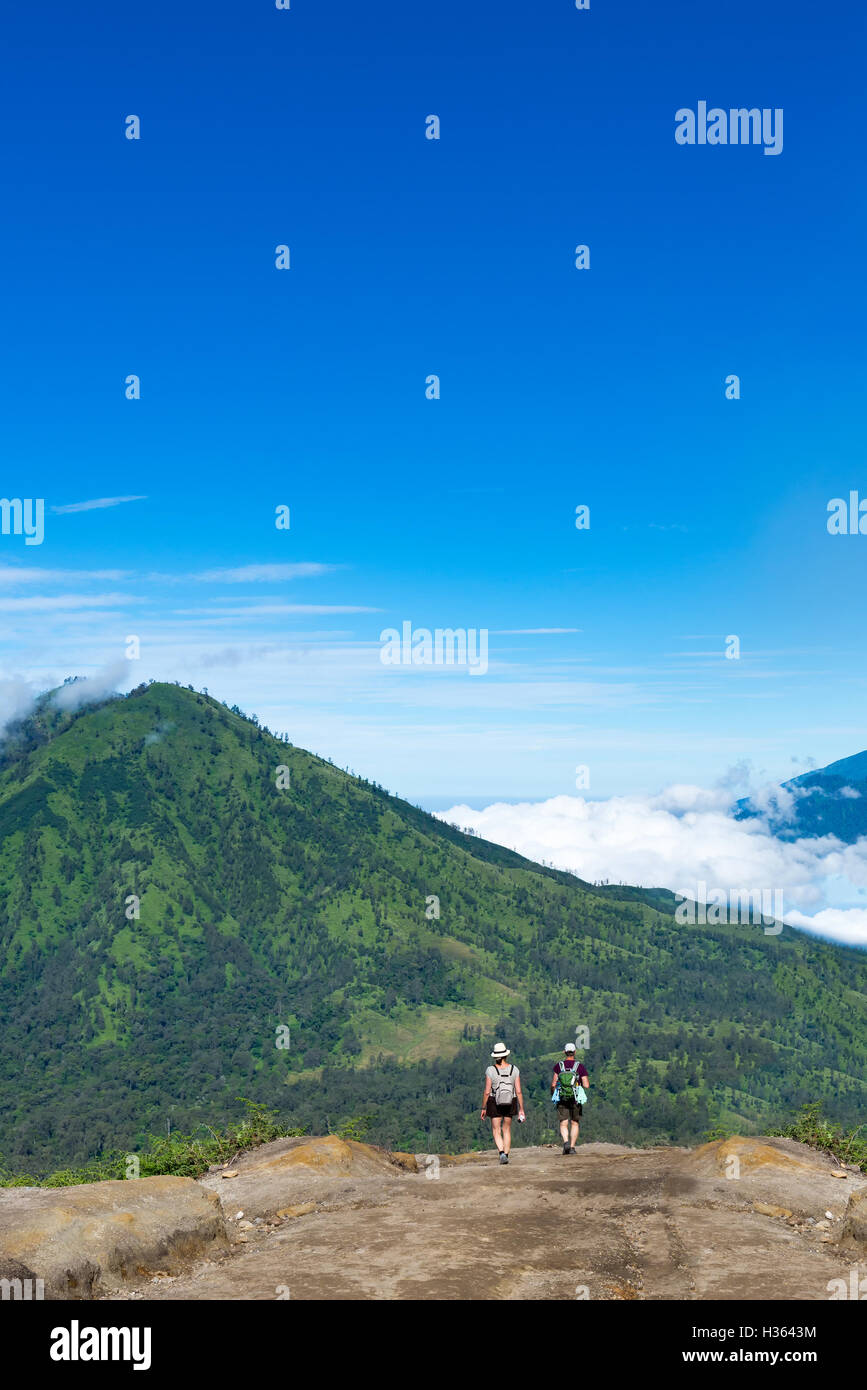 Group of hikers with backpacks walking in mountains. sky blue and ...